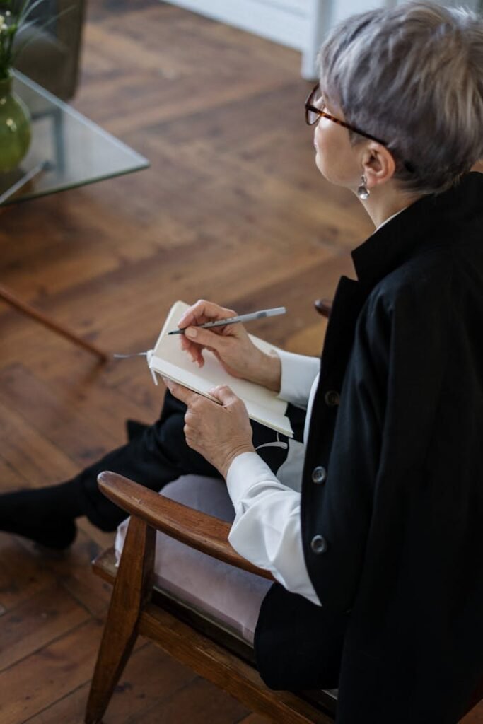 pexels-photo-4098148 A professional woman with glasses taking notes while seated indoors, depicting consultation or therapy.